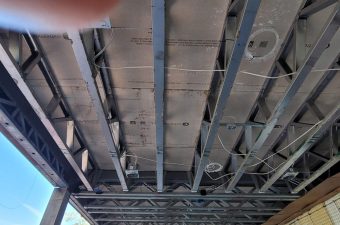 Exposed ceiling with ducts, pipes, and wiring in an industrial setting.
