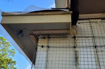 Worn-out gutter and roof corner with visible damage and debris.