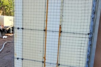 A construction wall frame with steel reinforcement bars and wire mesh.