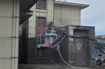 Workers on a suspended platform performing building maintenance.