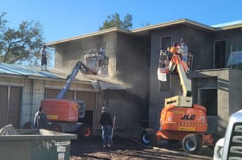 Construction workers demolishing a house using heavy machinery.
