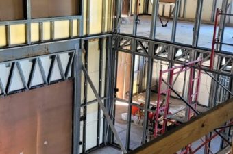 Construction site with exposed steel framework and scaffolding inside a building.