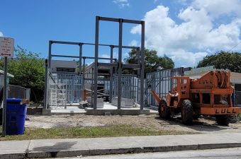 Construction site with steel framework and machinery under blue sky.