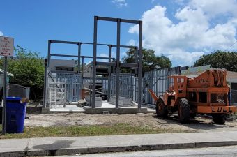 Construction site with steel framework and machinery under blue sky.