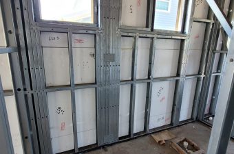 Construction site wall framing with insulation panels installed.