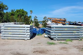 Stacks of metal beams and construction materials outdoors under a clear sky.