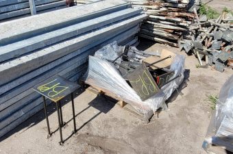 Stacked metal beams and a covered object at a construction site.