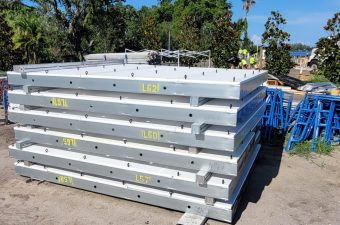 Stacked white metal or plastic panels outdoors under trees.