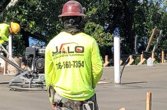 Construction worker in neon yellow JALO shirt and red helmet.