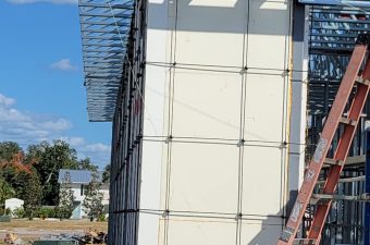 Construction site with scaffolding and a partially built wall on a sunny day.