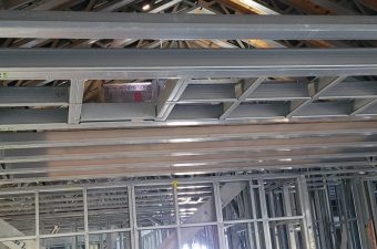 Exposed ceiling structure with metal framing and insulation in a building under construction.