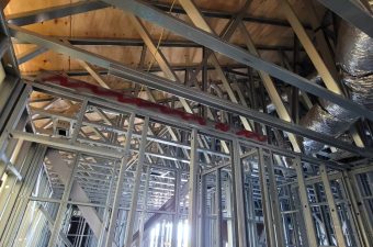 Exposed metal framing and wooden ceiling beams in a building under construction.