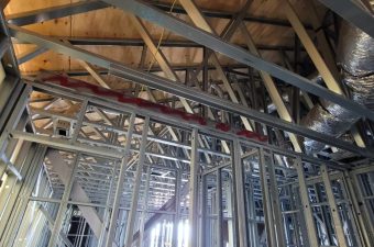 Exposed metal framing and wooden ceiling beams in a building under construction.