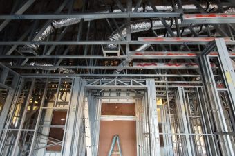 Interior view of a building under construction with exposed metal studs and beams.