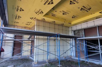 Scaffolding inside a room under construction with insulation on the ceiling.