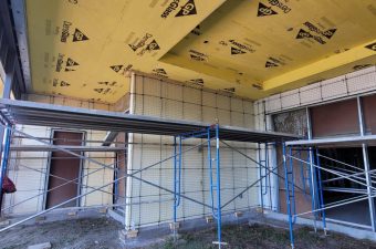 Scaffolding inside a room under construction with insulation on the ceiling.