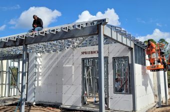 Man working on the roof of a partially constructed building with steel framework.