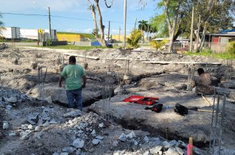 Construction workers at a deep excavation site with equipment and rubble.