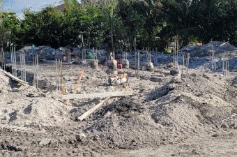 Construction site with piles of dirt and rebar structures under clear sky.