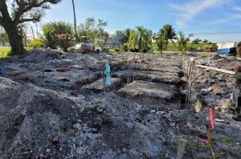 Excavation site with exposed foundations and a water bottle amid cleared land.