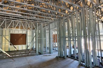 Interior view of a building under construction with metal framing and trusses.