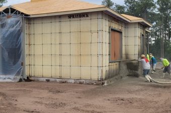 A construction site with walls insulated by spray foam and wooden window frames.