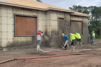 Workers spraying a textured finish on a building's exterior walls.