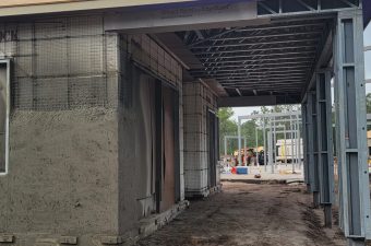 Construction site with concrete walls and scaffolding under a building.