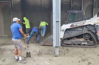 Workers pouring and leveling concrete indoors with machinery and tools.