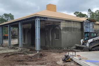 A building under construction with metal framework and concrete walls.