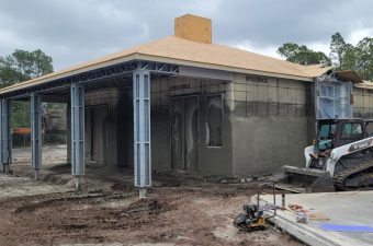A building under construction with metal framework and concrete walls.