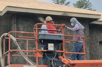 Two men working on scaffolding near a building wall.