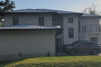 Modern two-story house with a metal roof and a parked car.