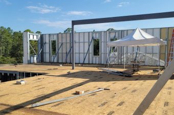 Construction site with metal framing and temporary walls under a clear sky.