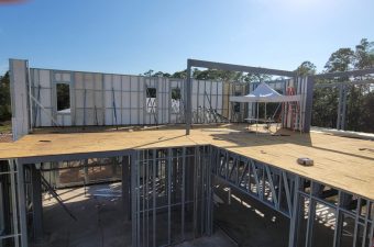 Steel framing construction in progress at a building site under clear skies.