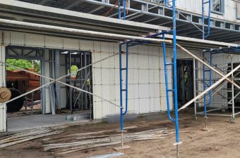 Construction site with scaffolding and workers installing windows.