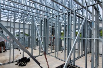 Steel frame structure under construction with workers inside.