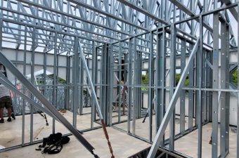 Steel frame structure under construction with workers inside.