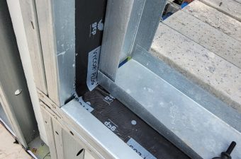 Close-up of a door hinge and frame with screws and a lock mechanism.
