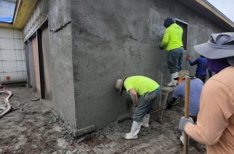 Two workers plastering a concrete wall.