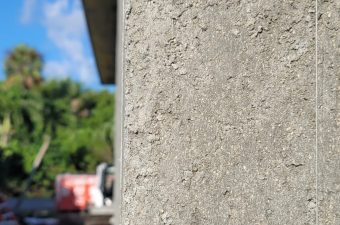 Close-up of textured concrete wall with blurred outdoor background.