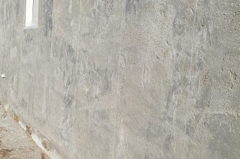 Plain concrete wall with a small window near the top.
