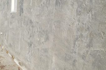 Plain concrete wall with a small window near the top.