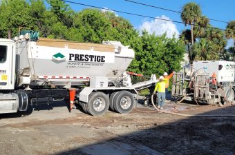 Workers operating a Prestige cement mixer at a construction site.