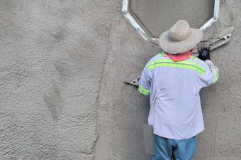 Man working on a wall near a circular opening.
