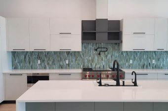 Modern kitchen with white cabinets and a blue patterned backsplash.