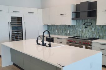 Modern kitchen with sleek white countertops and a stylish backsplash.
