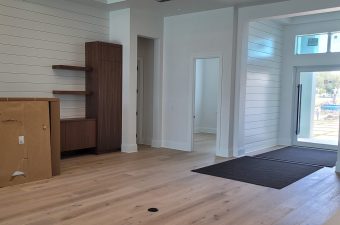 Spacious modern room with wooden flooring and white walls.