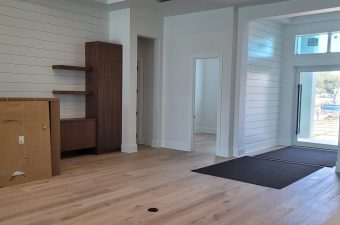 Spacious modern room with wooden flooring and white walls.