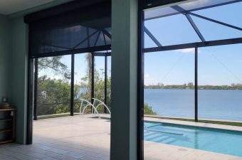 A serene poolside view overlooking a calm lake through glass panels.